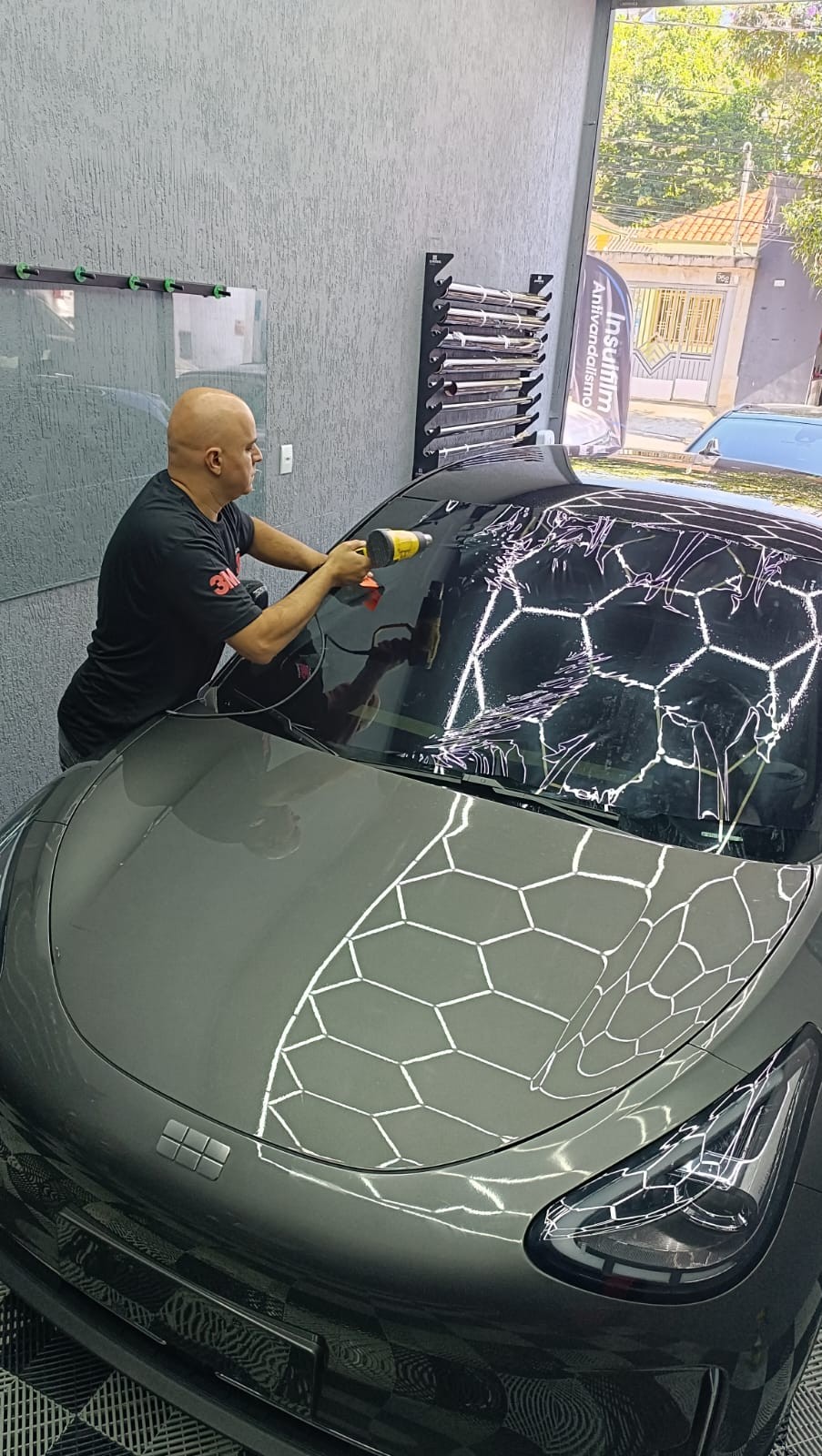 Técnico aplicando insulfilm no para-brisa e capô do veículo